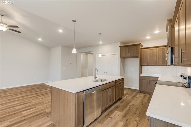 kitchen featuring a kitchen island with sink, sink, light hardwood / wood-style flooring, appliances with stainless steel finishes, and decorative light fixtures