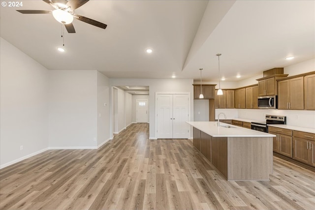 kitchen with sink, stainless steel appliances, an island with sink, pendant lighting, and light hardwood / wood-style floors