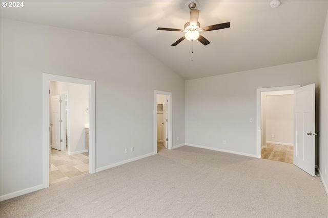 unfurnished bedroom with ceiling fan, light colored carpet, a spacious closet, and vaulted ceiling