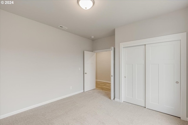 unfurnished bedroom with light carpet and a closet