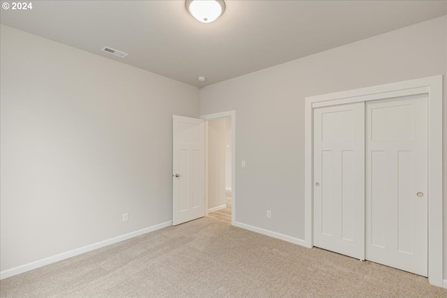 unfurnished bedroom with light carpet and a closet