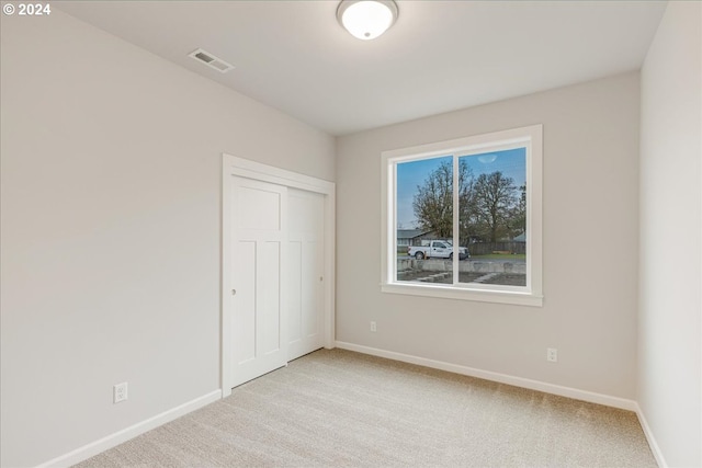 unfurnished bedroom featuring light colored carpet and a closet