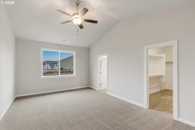 unfurnished bedroom with a walk in closet, light colored carpet, vaulted ceiling, ceiling fan, and a closet