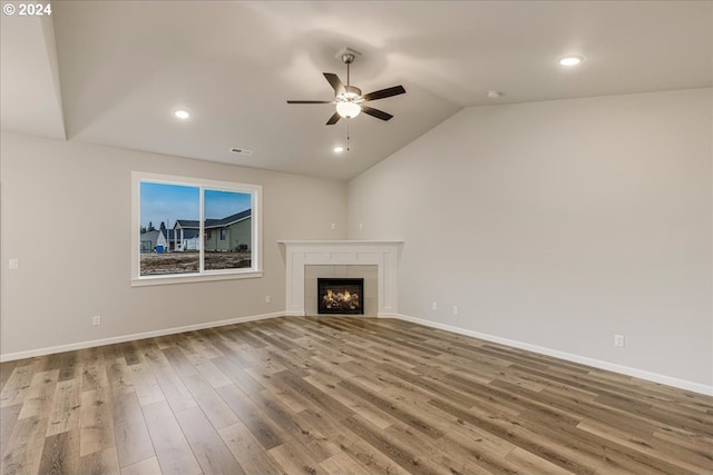 unfurnished living room featuring ceiling fan, wood-type flooring, a fireplace, and vaulted ceiling