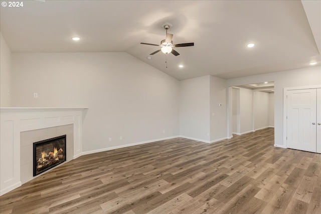 unfurnished living room with hardwood / wood-style floors, ceiling fan, lofted ceiling, and a tile fireplace