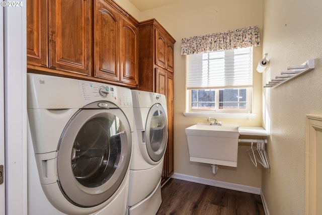 clothes washing area with washer and clothes dryer, sink, cabinets, and dark wood-type flooring