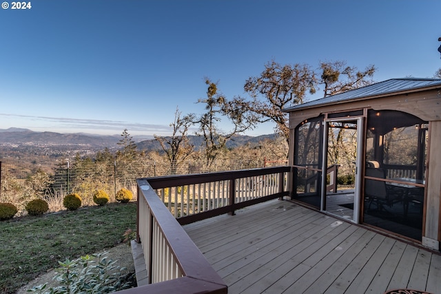 wooden deck featuring a mountain view and a sunroom