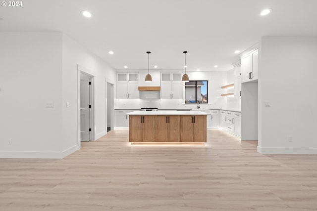 kitchen featuring light wood-type flooring, a kitchen island, white cabinetry, and pendant lighting