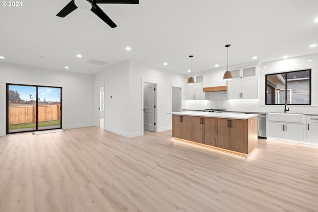 kitchen featuring pendant lighting, a center island, white cabinetry, sink, and ceiling fan