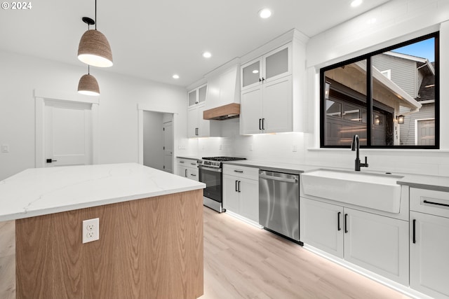 kitchen featuring decorative light fixtures, white cabinets, a center island, and stainless steel appliances