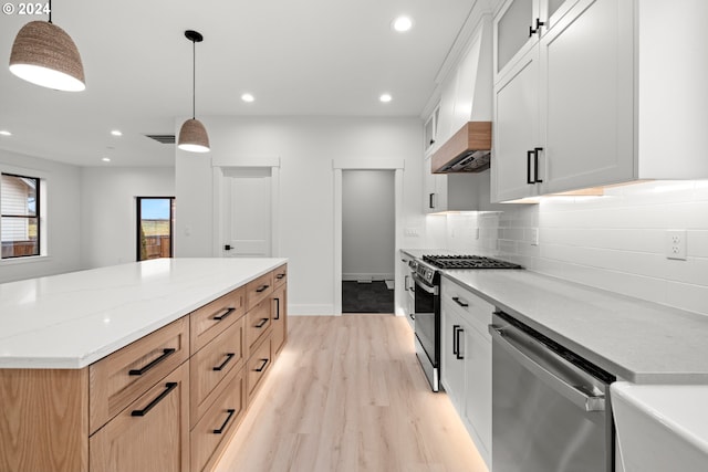 kitchen with light stone counters, white cabinetry, pendant lighting, and stainless steel appliances