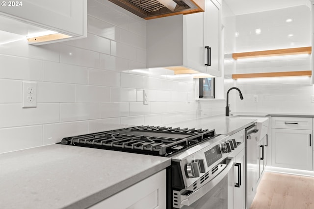 kitchen featuring premium range hood, white cabinets, sink, gas stove, and backsplash