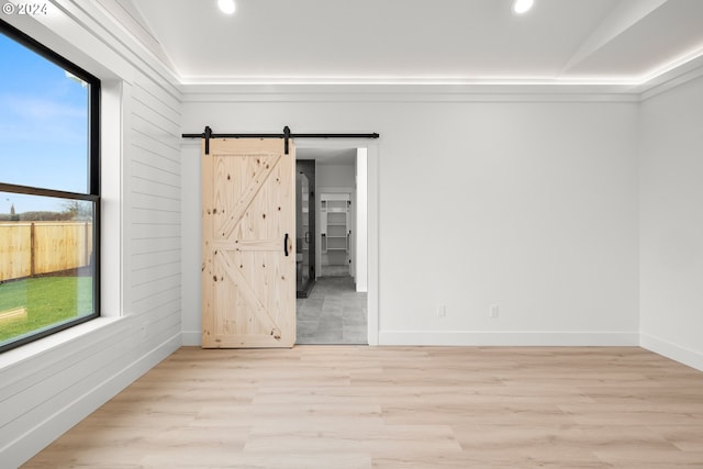 empty room featuring a barn door and light hardwood / wood-style floors