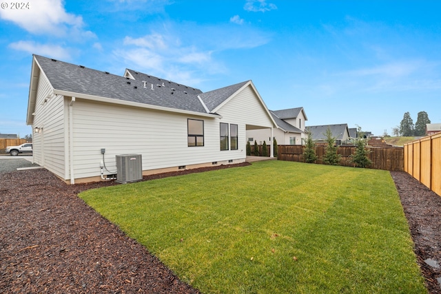 back of house with central air condition unit and a lawn