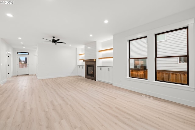 unfurnished living room featuring ceiling fan, light hardwood / wood-style flooring, and a fireplace