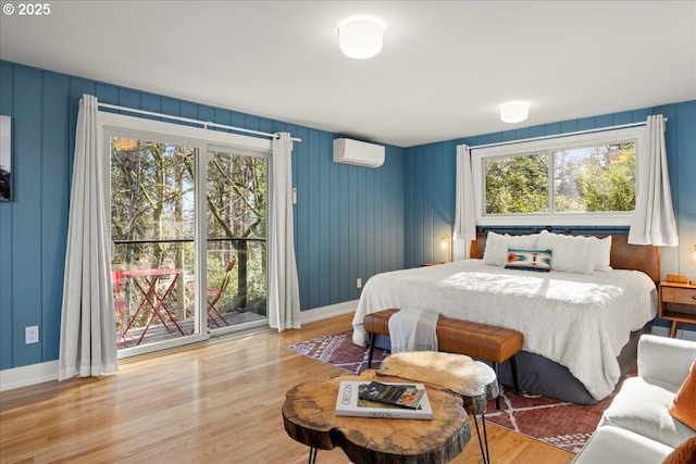 bedroom with a wall mounted air conditioner, wood finished floors, and baseboards