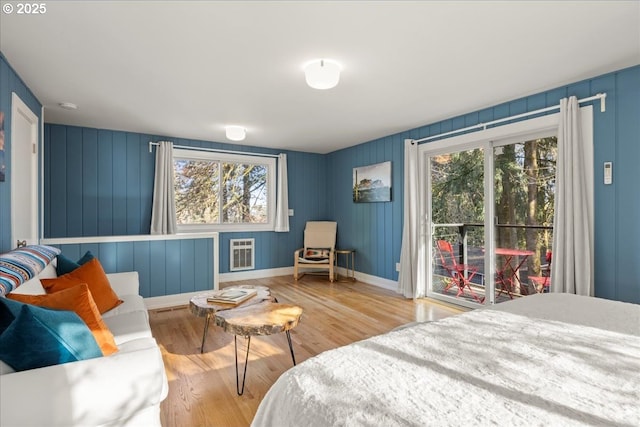 bedroom with multiple windows, light hardwood / wood-style flooring, and heating unit