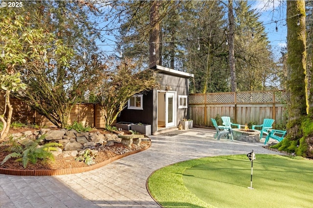 view of patio featuring a fenced backyard, an outdoor structure, and a fire pit