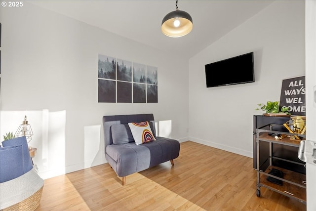 living area featuring baseboards, vaulted ceiling, and wood finished floors