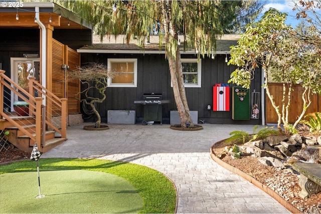 exterior space featuring a patio, a shingled roof, board and batten siding, and fence