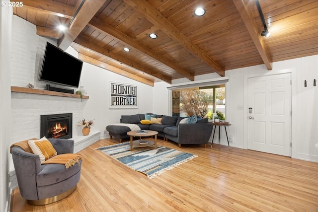 living room featuring wood ceiling, hardwood / wood-style flooring, lofted ceiling with beams, and a brick fireplace