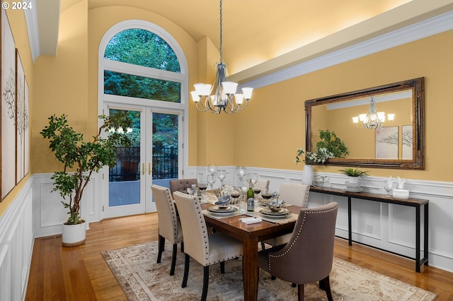 dining room featuring high vaulted ceiling, a chandelier, french doors, and light hardwood / wood-style flooring