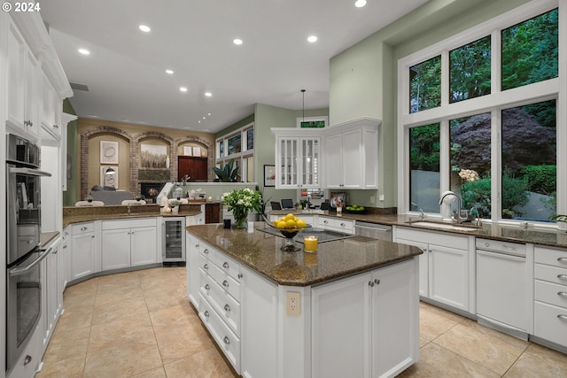 kitchen with beverage cooler, white cabinets, a center island, and sink