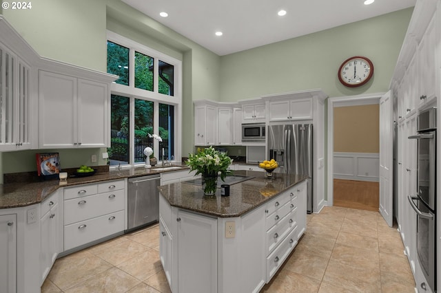 kitchen featuring dark stone countertops, stainless steel appliances, a healthy amount of sunlight, and white cabinetry