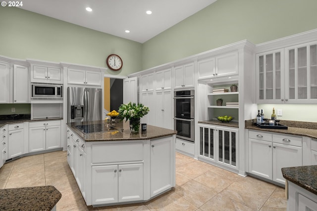 kitchen featuring appliances with stainless steel finishes, dark stone countertops, and white cabinetry