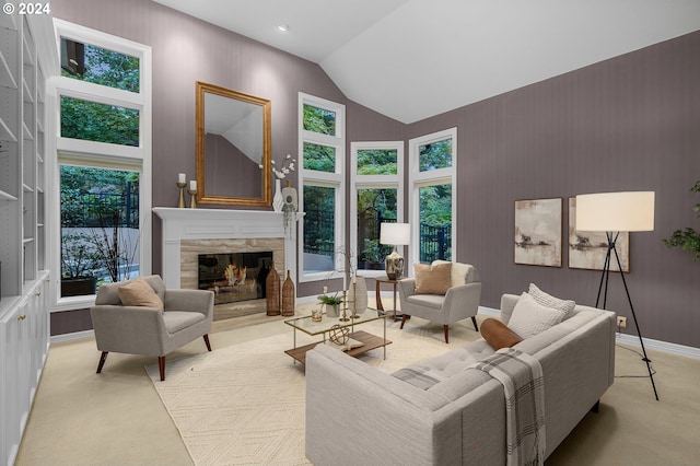 living room with a stone fireplace, light colored carpet, and high vaulted ceiling