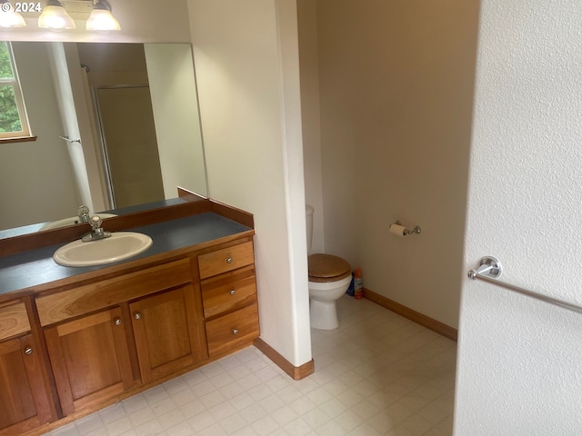 bathroom featuring baseboards, a stall shower, toilet, and vanity