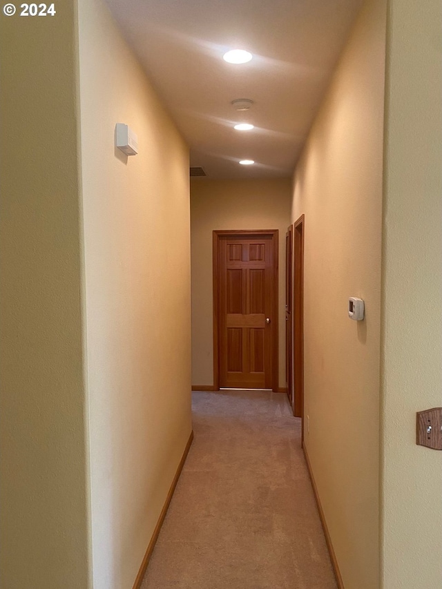 corridor featuring baseboards and light colored carpet