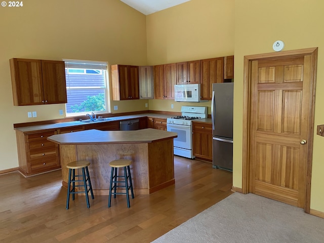 kitchen with a sink, high vaulted ceiling, brown cabinets, and white appliances