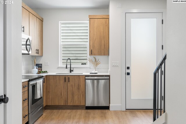 kitchen with sink, appliances with stainless steel finishes, and light hardwood / wood-style floors