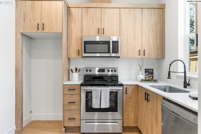 kitchen featuring sink, appliances with stainless steel finishes, light wood-type flooring, and light brown cabinets