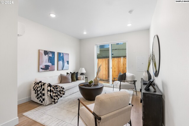 living room featuring a wall mounted air conditioner and light wood-type flooring