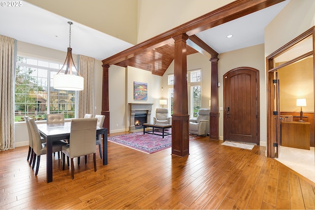 dining room featuring lofted ceiling with beams, light wood-type flooring, and decorative columns