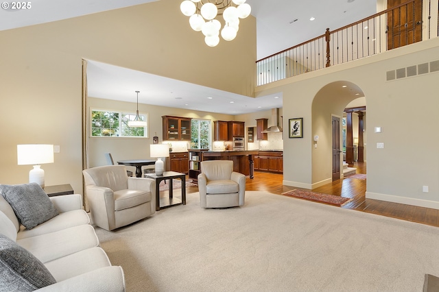 living room featuring a high ceiling, an inviting chandelier, and light hardwood / wood-style flooring