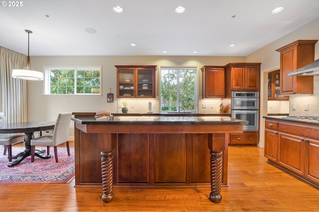 kitchen with stainless steel appliances, a kitchen island, backsplash, and hanging light fixtures