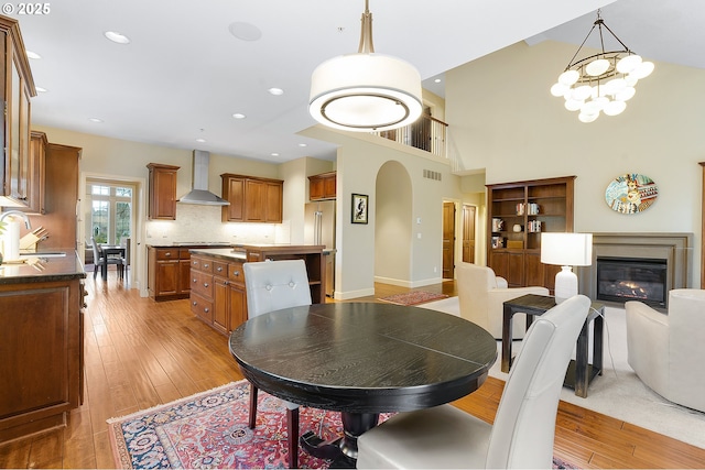 dining room featuring sink, light hardwood / wood-style flooring, a chandelier, and a high ceiling