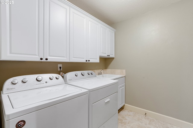 clothes washing area with sink, a textured ceiling, separate washer and dryer, and cabinets