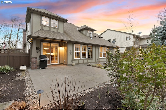 back house at dusk featuring a patio