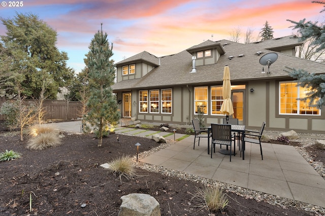 back house at dusk featuring a patio area