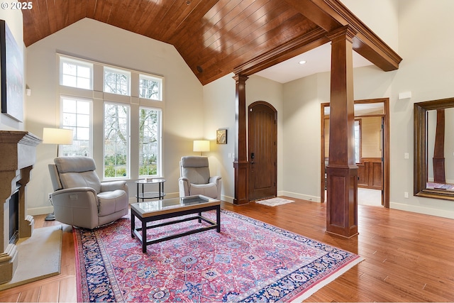 living room with decorative columns, high vaulted ceiling, light hardwood / wood-style floors, and wooden ceiling