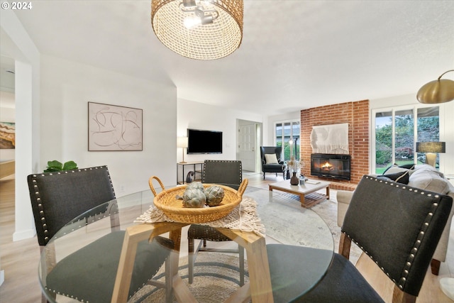 dining room featuring a brick fireplace and light hardwood / wood-style floors