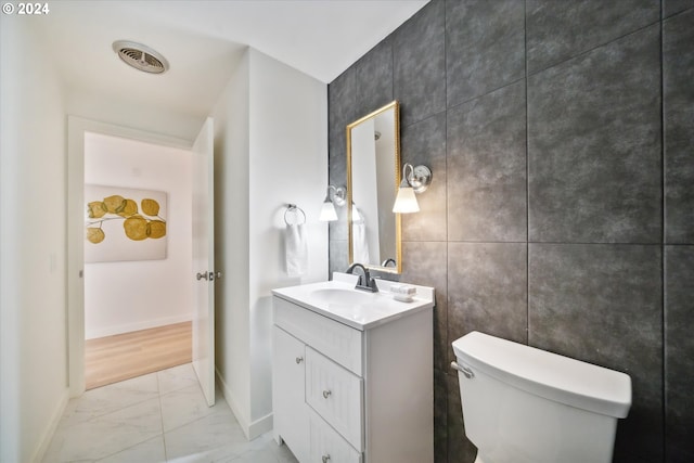 bathroom with vanity, tile walls, and toilet