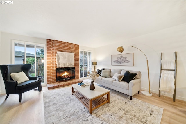 living room with a brick fireplace and light wood-type flooring