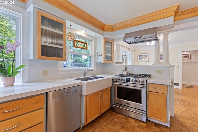 kitchen with crown molding, stainless steel appliances, light countertops, a sink, and wall chimney exhaust hood