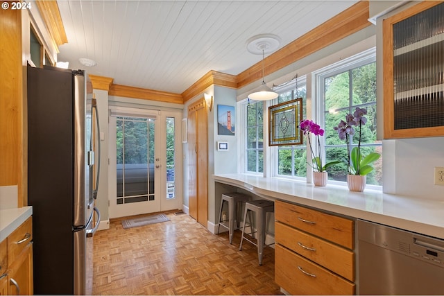 kitchen featuring light countertops, appliances with stainless steel finishes, ornamental molding, glass insert cabinets, and built in study area