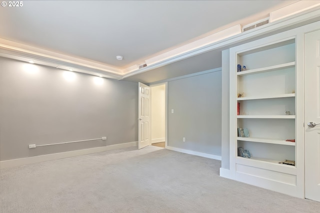 carpeted empty room featuring baseboards, visible vents, and built in features